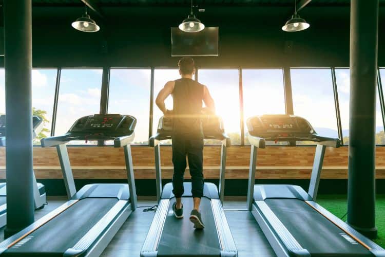 Rear View Of Man Running On Treadmill by a Window In a Gym